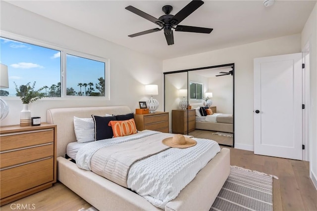 bedroom featuring light wood-type flooring, ceiling fan, baseboards, and a closet