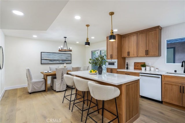 kitchen featuring light countertops, light wood-style floors, a sink, dishwasher, and a kitchen breakfast bar