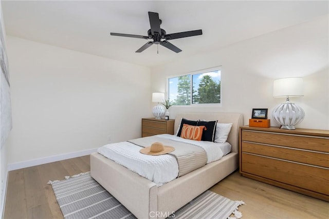 bedroom with light wood-style flooring, baseboards, and a ceiling fan