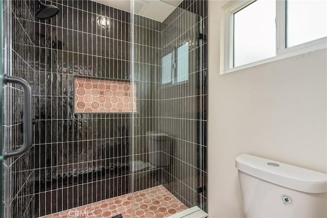 bathroom with a tile shower and toilet