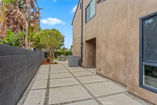 view of home's exterior with stucco siding, a fenced backyard, central AC unit, and a patio