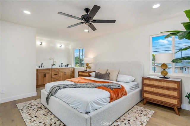 bedroom featuring light wood-style flooring, baseboards, a sink, and recessed lighting