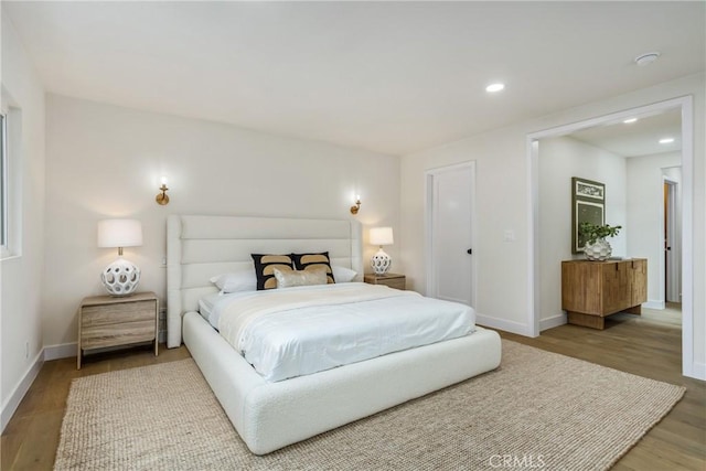 bedroom with baseboards, wood finished floors, and recessed lighting