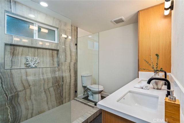 full bathroom featuring double vanity, visible vents, toilet, a sink, and a walk in shower