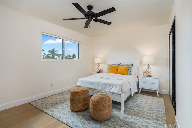 bedroom featuring ceiling fan, baseboards, and wood finished floors