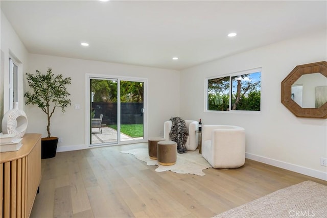 sitting room with baseboards, wood finished floors, and a healthy amount of sunlight