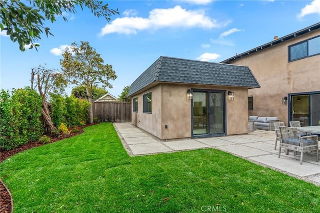 rear view of house with roof with shingles, a yard, mansard roof, a patio area, and a fenced backyard