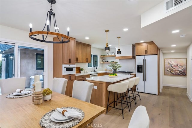 kitchen with white appliances, visible vents, a center island, light wood-style floors, and open shelves