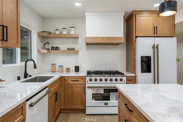 kitchen featuring premium range hood, white appliances, a sink, and light stone countertops