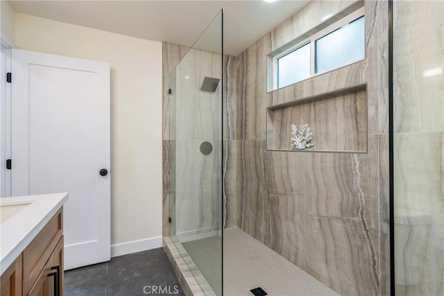 bathroom with tile patterned flooring, a marble finish shower, baseboards, and vanity