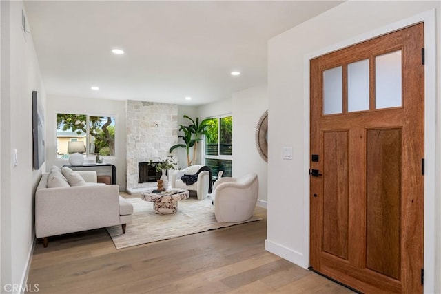 foyer entrance featuring visible vents, baseboards, light wood-type flooring, a fireplace, and recessed lighting