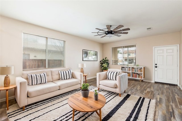 living room featuring a ceiling fan, visible vents, wood finished floors, and baseboards