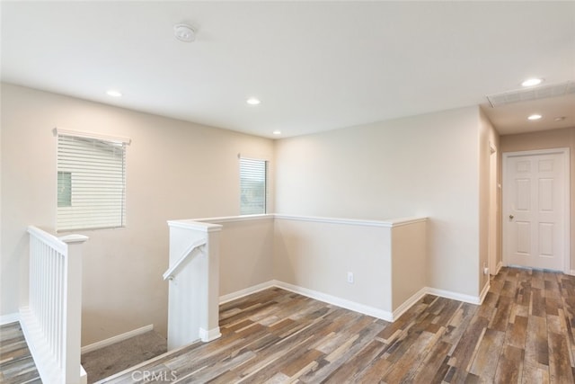 corridor featuring wood finished floors, recessed lighting, an upstairs landing, and baseboards