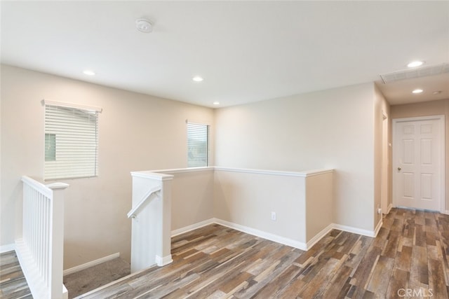 hall with baseboards, recessed lighting, wood finished floors, and an upstairs landing