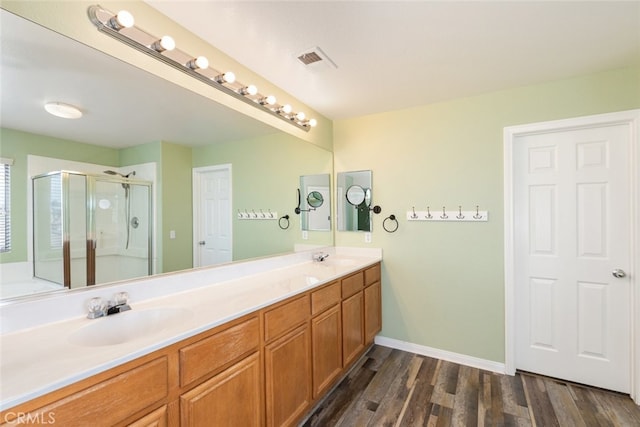 full bath featuring a sink, a stall shower, double vanity, visible vents, and wood finished floors