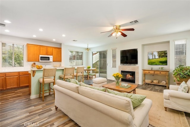 living room with visible vents, a wealth of natural light, recessed lighting, wood finished floors, and a glass covered fireplace