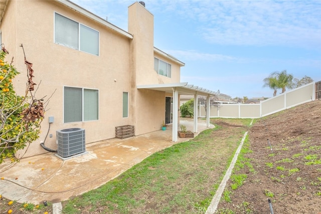 back of property with a patio, a yard, a fenced backyard, central AC, and stucco siding