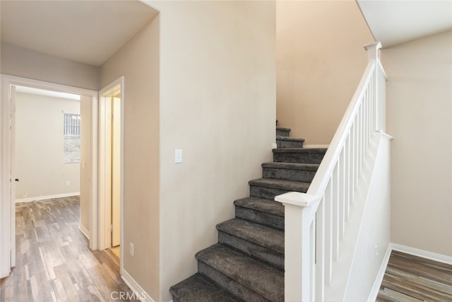 staircase with wood finished floors and baseboards