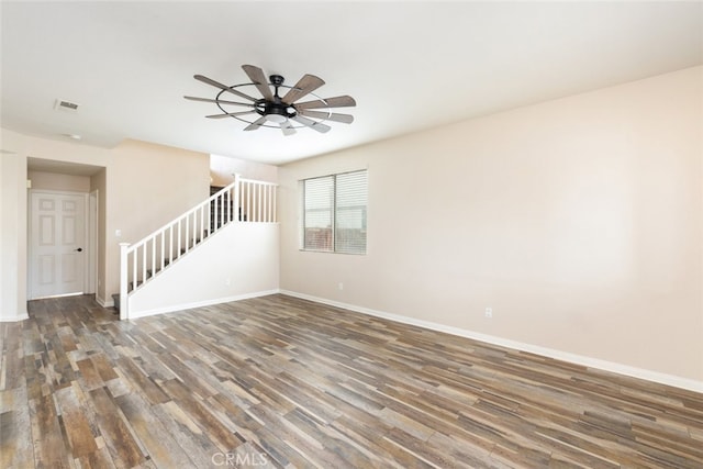 empty room featuring stairway, baseboards, visible vents, and wood finished floors