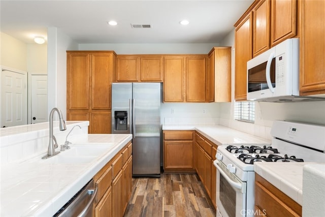 kitchen with dark wood-style flooring, visible vents, stainless steel appliances, and tile countertops