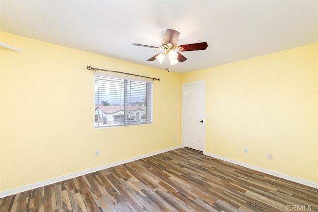 spare room with wood finished floors, a ceiling fan, and baseboards