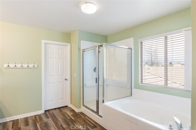 full bathroom featuring wood finished floors, a garden tub, a shower stall, and baseboards