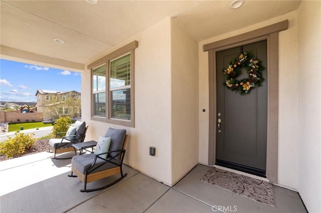 property entrance with covered porch and stucco siding