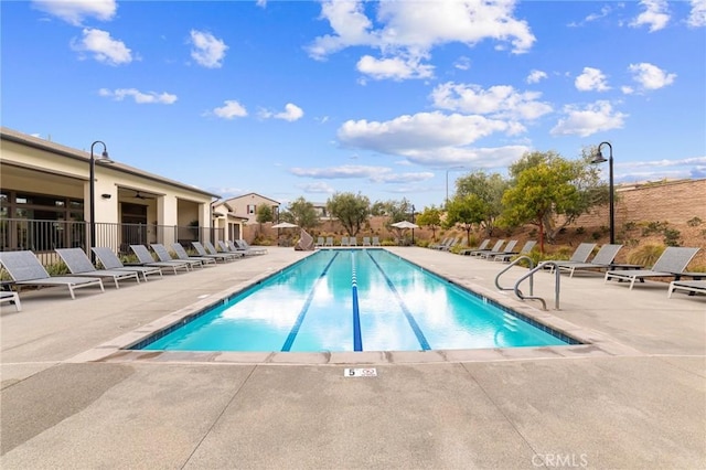 community pool with a patio area and fence