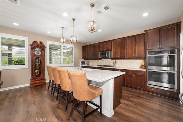 kitchen with a wealth of natural light, appliances with stainless steel finishes, visible vents, and decorative backsplash