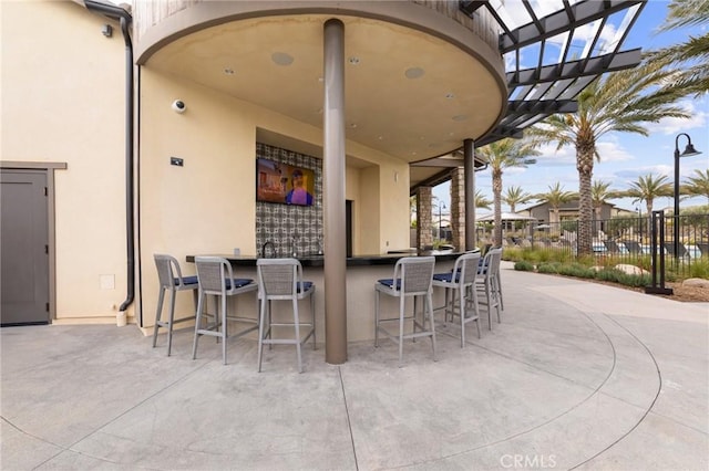 view of patio / terrace featuring outdoor dry bar, fence, and a pergola