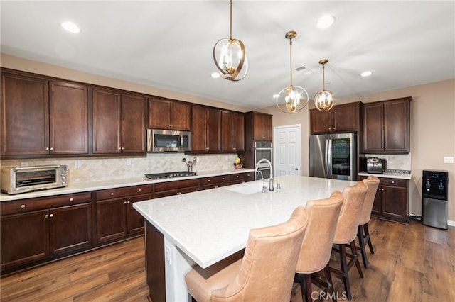 kitchen with appliances with stainless steel finishes, dark wood finished floors, a toaster, and a sink