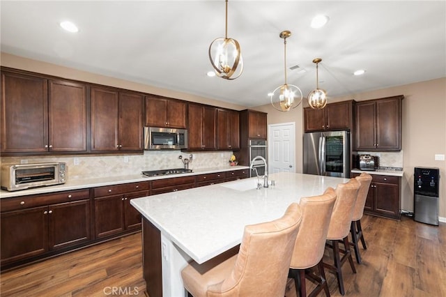 39601 Lupine Dr, Temecula, CA 92591 - kitchen with stainless steel appliances, a sink, dark wood-type flooring, tasteful backsplash, and a breakfast bar area