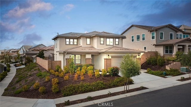 prairie-style house with driveway, a garage, a residential view, fence, and stucco siding