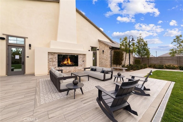 view of patio featuring an outdoor living space with a fireplace and fence