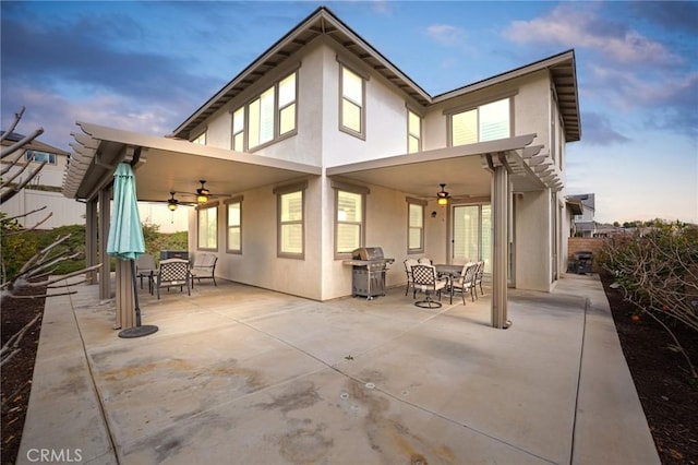 back of property featuring a ceiling fan, outdoor dining space, a patio, and stucco siding