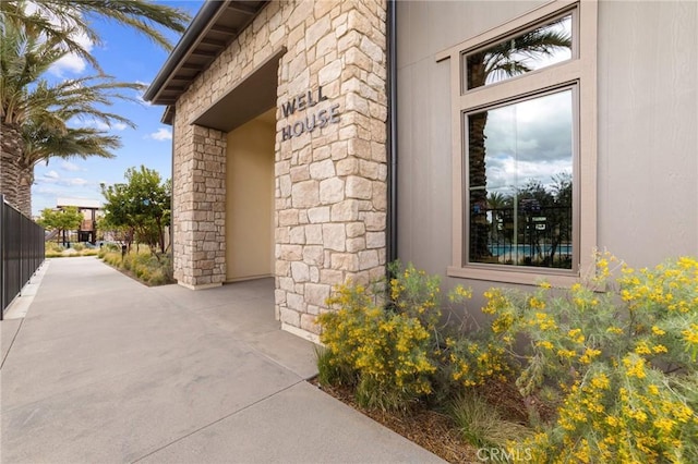 entrance to property with stone siding and fence