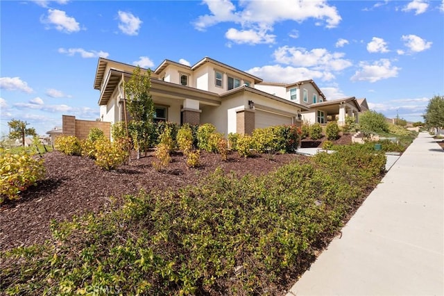 view of side of property featuring an attached garage, stucco siding, and brick siding