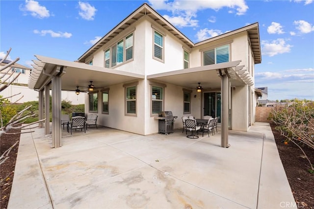 rear view of house with a patio, fence, a ceiling fan, and stucco siding