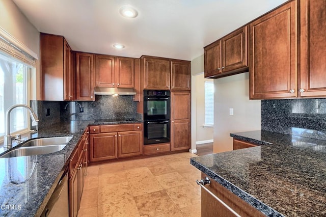 kitchen with under cabinet range hood, a sink, backsplash, black appliances, and dark stone countertops