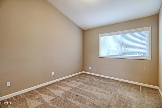 carpeted spare room with lofted ceiling and baseboards