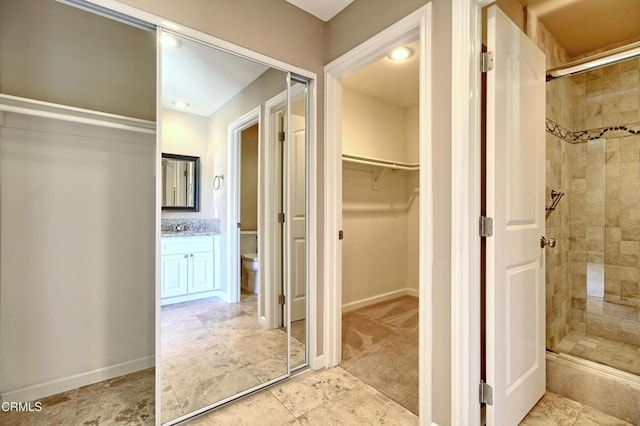 full bath featuring toilet, vanity, baseboards, a spacious closet, and a shower stall