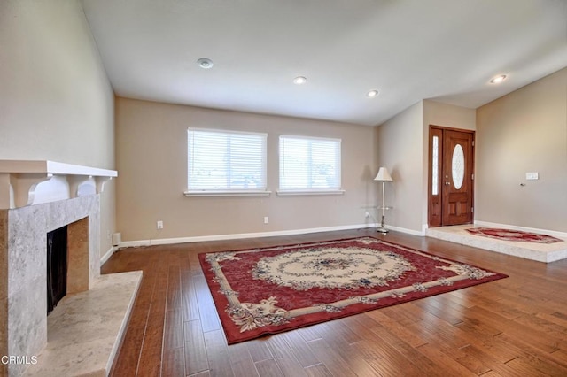 foyer entrance featuring wood-type flooring, a fireplace, baseboards, and recessed lighting