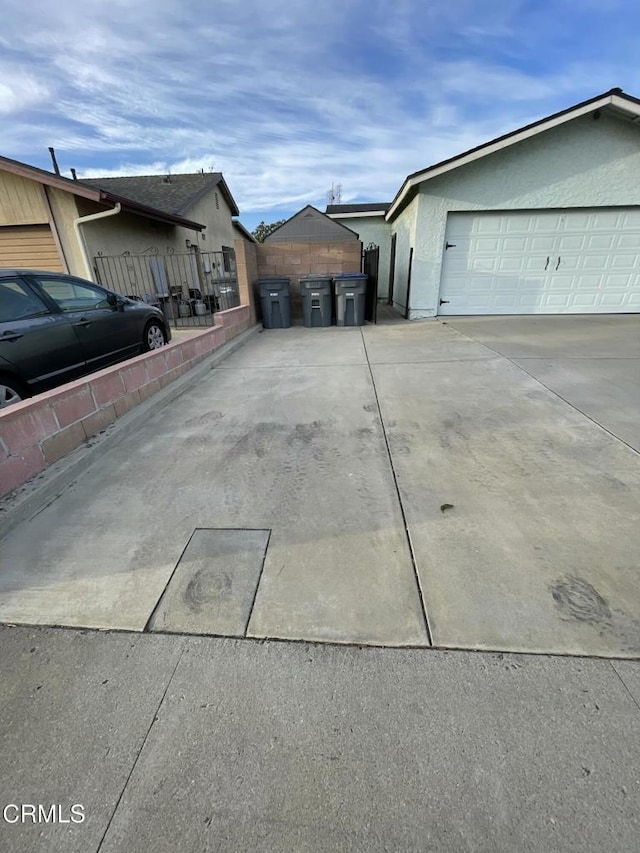 view of side of property with a garage, an outbuilding, fence, and stucco siding