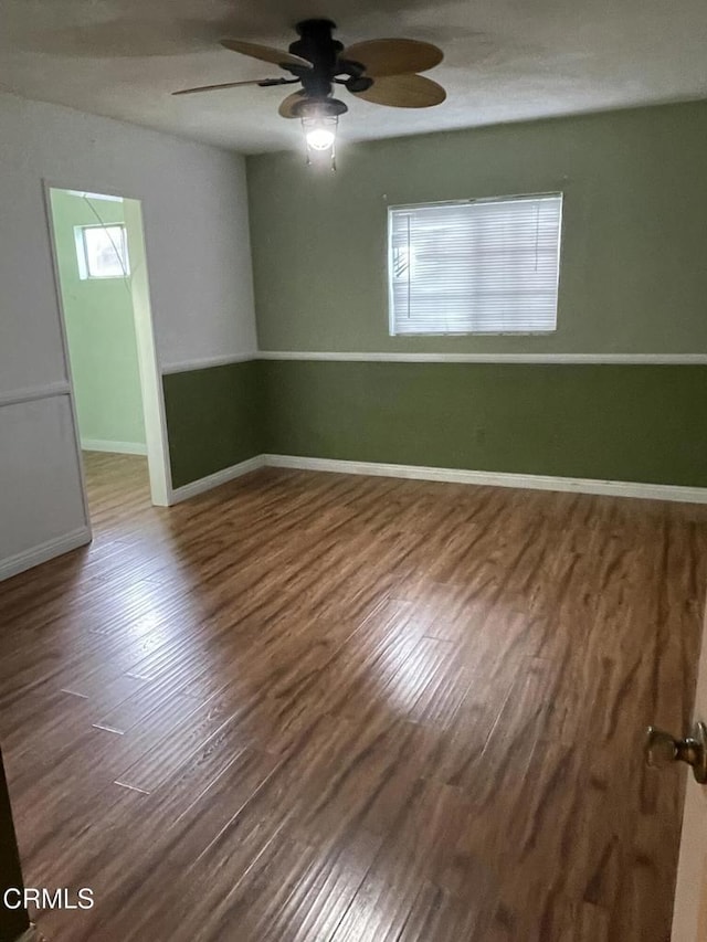 spare room featuring a ceiling fan, baseboards, and wood finished floors