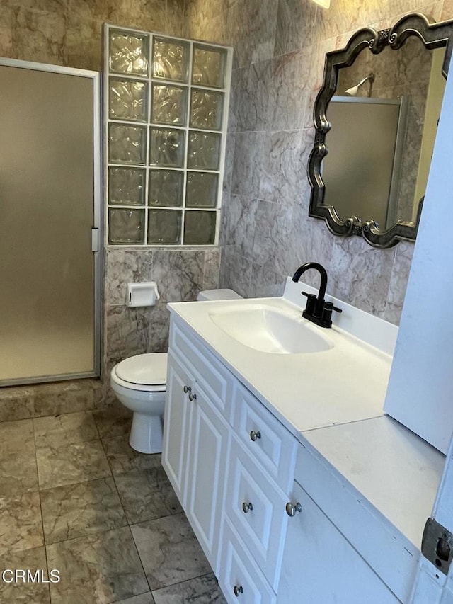 bathroom with a stall shower, toilet, tile walls, and vanity