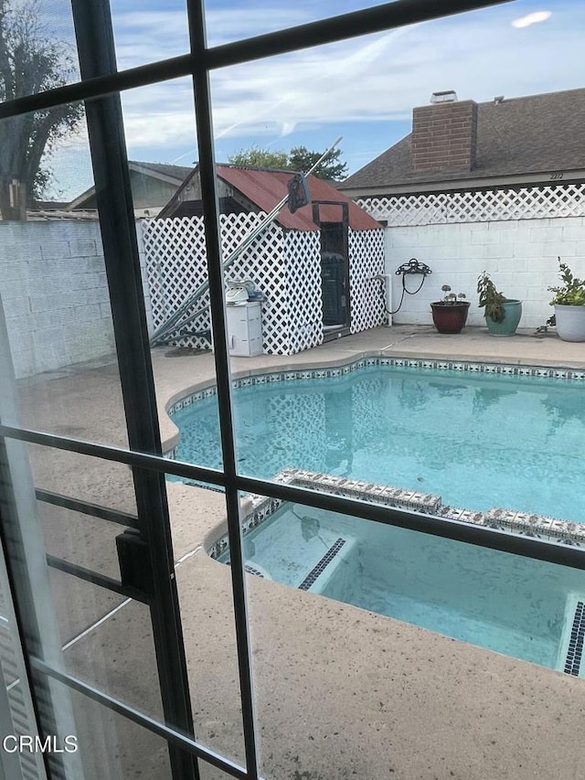 view of swimming pool featuring glass enclosure and a pool with connected hot tub