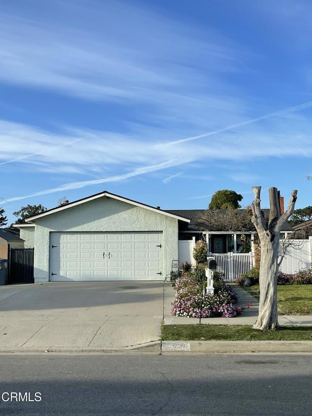 ranch-style house featuring driveway, a garage, fence, and stucco siding