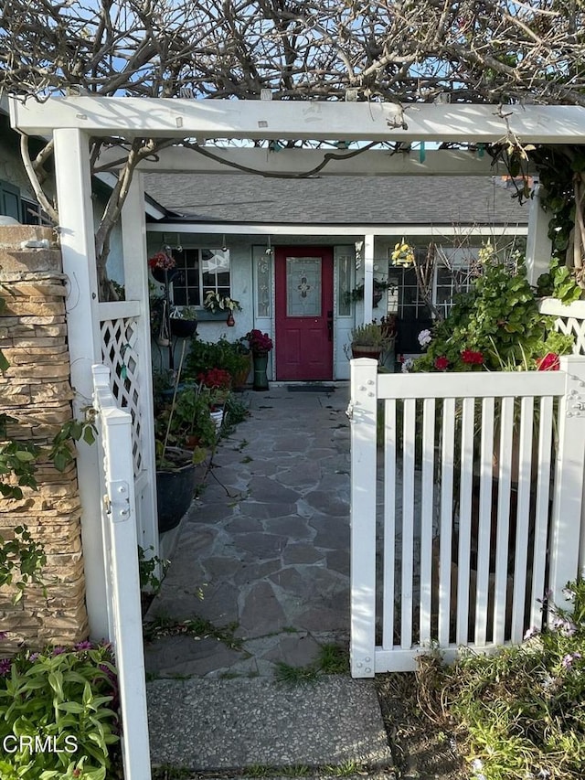 view of exterior entry featuring a shingled roof