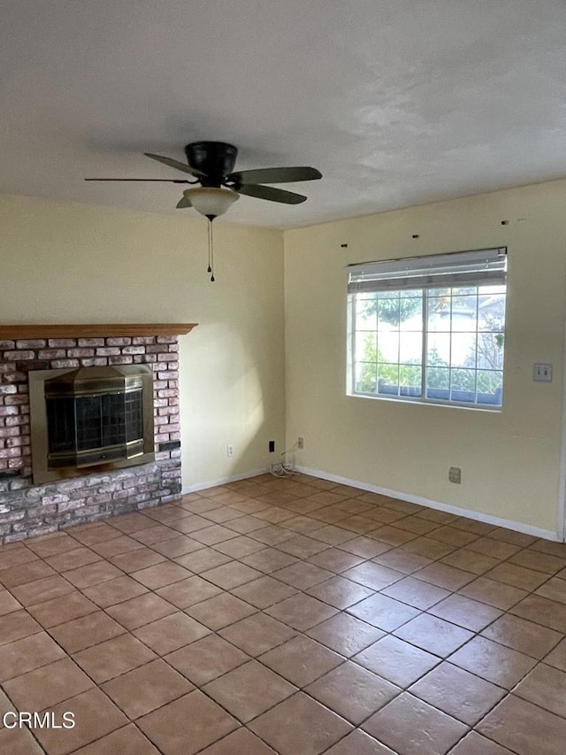 unfurnished living room with a ceiling fan, tile patterned flooring, a fireplace, and baseboards