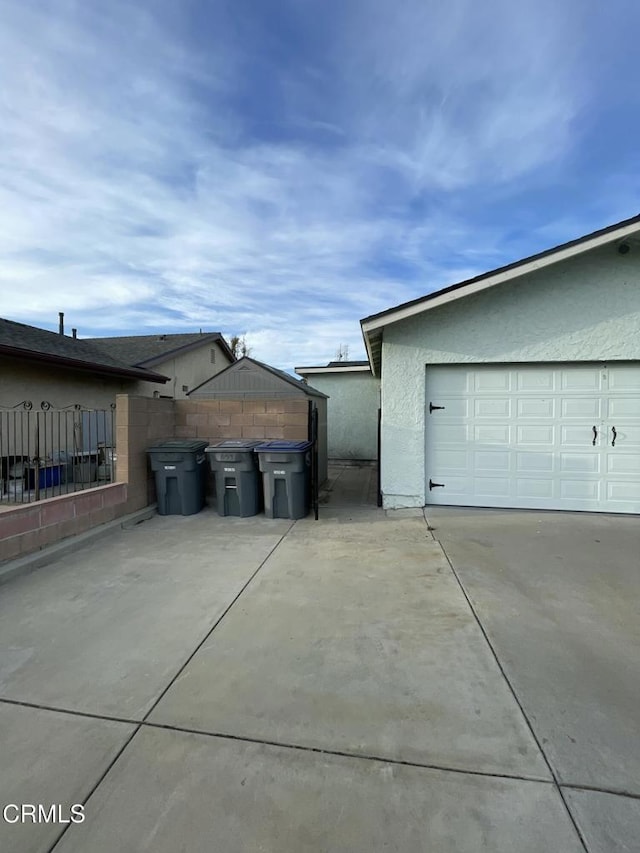 view of home's exterior with a garage, fence, and stucco siding